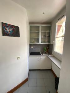Una cocina con gabinetes blancos y un fregadero y una ventana. en Studio Proche Paris, en Chaville