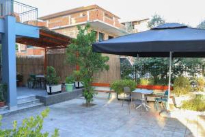 un patio con sombrilla, mesa y sillas en Albora Guest House en Fier