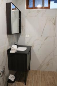 uma casa de banho com um lavatório preto e paredes em mármore em Albora Guest House em Fier