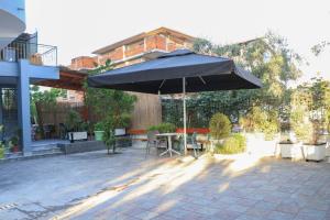 un patio con mesa y sombrilla en Albora Guest House en Fier