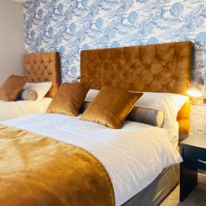 a bedroom with a large bed with gold pillows at Gray's at Bushmills in Bushmills