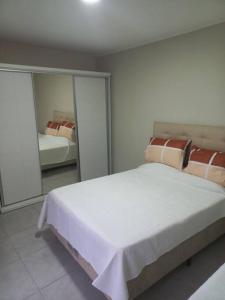 a bedroom with a large white bed and a mirror at Casa amplia y bien ubicada in Artigas