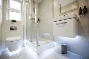 a white bathroom with a shower and a toilet at Elm House in Reading