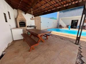 a patio with a wooden table and a swimming pool at Linda casa com piscina in São Miguel do Gostoso