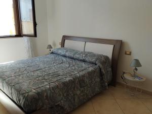 um quarto com uma cama e uma mesa com um candeeiro em Villa Madreselva em Cinisi