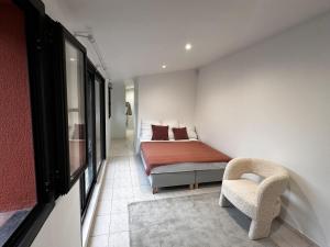 ein kleines Schlafzimmer mit einem Bett und einem Stuhl in der Unterkunft Villa avec jardin in Saint-Cloud
