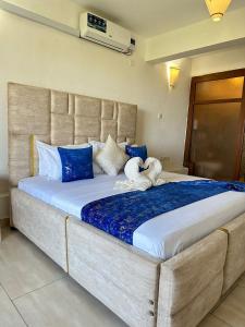 a large bed with blue and white pillows at Imani Front Beach Appartment in Diani Beach
