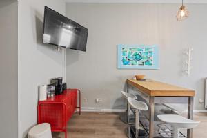 a dining room with a red table and a tv on the wall at primeflats - Apartment Langhans Berlin-Weißensee in Berlin