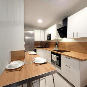 une cuisine avec des placards blancs et un comptoir en bois dans l'établissement La perle d'Eybens, à Eybens