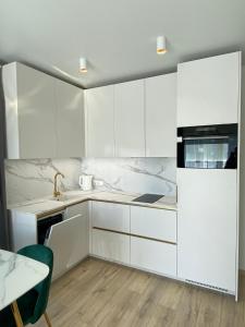 a white kitchen with white cabinets and a table at Laiminga banga in Palanga