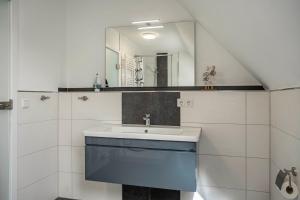 a bathroom with a sink and a mirror at 5 Sterne Ferienwohnung Boddenblick in Glowe +14 photos