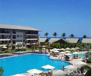 a large swimming pool with umbrellas and a hotel at Beach Class Eco Life in Porto De Galinhas