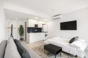 a white bedroom with a bed and a couch at MADRIVER apartamentos reformados con parking gratuito in Madrid