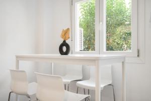 a white table with white chairs and a window at MADRIVER apartamentos reformados con parking gratuito in Madrid