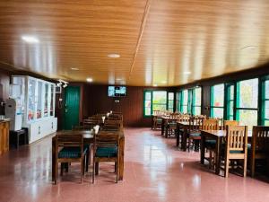 een eetkamer met houten tafels, stoelen en ramen bij Himalayan High, Auli, By Himalayan Eco Lodges in Joshimath