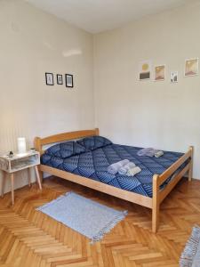 Bett mit blauer Decke in einem Zimmer in der Unterkunft Apartman Merkur in Vrnjačka Banja