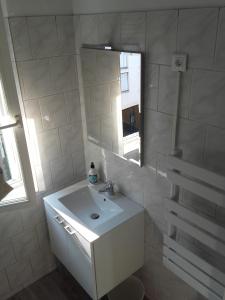 bagno bianco con lavandino e specchio di Bienvenus à Thèse - Appartement Bleu a Marsiglia