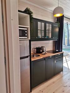 a kitchen with black cabinets and a stainless steel refrigerator at Patio Dębki in Dębki