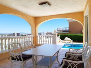 einen Balkon mit einem Tisch, Stühlen und einem Pool in der Unterkunft Villa de 2 plantas in Oropesa del Mar