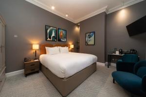 um quarto com uma cama grande e uma cadeira azul em The Scott em Edimburgo