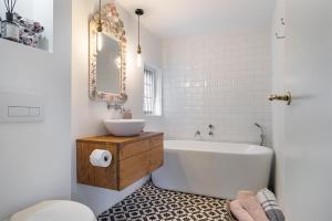 a bathroom with a white tub and a sink at Het Zeepaartje, knus en gezellig in Noordwijkerhout