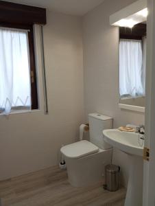 Baño blanco con aseo y lavamanos en apartamento Somo, en Somo