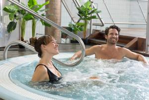 a man and a woman in a hot tub at Hôtel Les Sources in Vernet-les-Bains