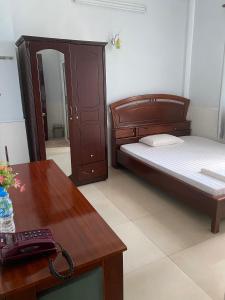 Schlafzimmer mit einem Bett, einem Schreibtisch und einem Telefon in der Unterkunft Khách sạn Tường Minh in Cao Lãnh