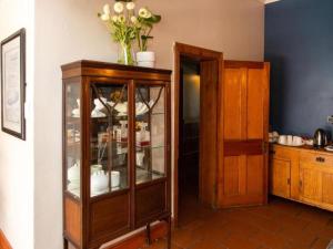 a wooden cabinet with a glass door in a room at Loddey`s Guest House in Strand