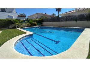 a swimming pool with blue water in front of a house at Villa Tropical in Comarruga