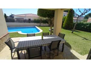 a table and chairs in a yard with a swimming pool at Villa Tropical in Comarruga