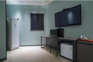 a kitchen with a desk and a television on the wall at HOTEL MYEONG JAK in Suwon