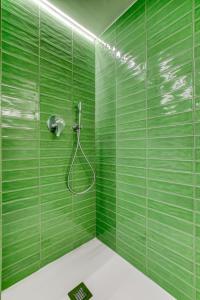 Baño de azulejos verdes con ducha y manguera en JL Hotel, en San Julián