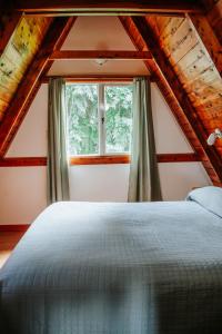 1 dormitorio con cama y ventana en Cabañas Nosotros en Lago Puelo