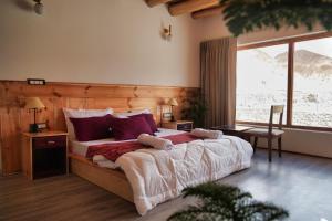 a bedroom with a large bed and a large window at The Hermit Homestay in Leh