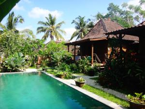 a villa with a swimming pool in front of a house at Lembah Sentosa in Ubud