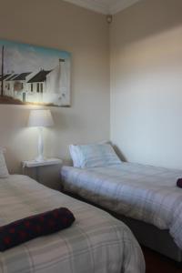 a bedroom with two beds and a painting on the wall at Harbour Views in Kalk Bay
