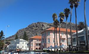 a building with palm trees in front of a mountain at Harbour Views in Kalk Bay