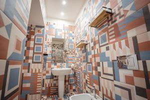 a bathroom with a sink and a colorful tile wall at P.C. Boutique Medina H. Napoli Centro, by Clapa Group in Naples +169 photos