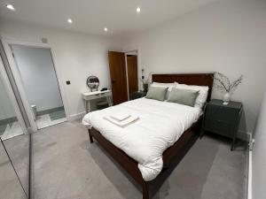 a bedroom with a large bed with white sheets at Hassocks House - Modern Detached 2 Bedroom House in Streatham in Streatham Vale