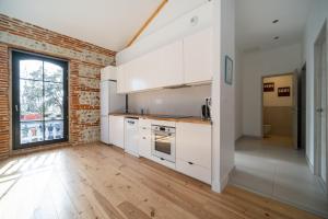 a kitchen with white cabinets and a brick wall at Évasions-Escapade, centre-ville, gare in Auterive