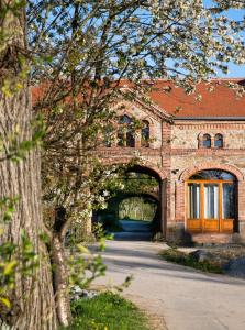 ein Backsteingebäude mit einem Torbogen vor einem Baum in der Unterkunft Historisches Rittergut Hexenburg Nähe Sächsische Schweiz, Dresden - mit Badeteich in Großharthau