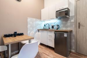 a small kitchen with white cabinets and a table at Main Square Teatralna - 2 room apartment with balcony - self-in - coffee and tea in Katowice