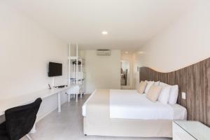 1 dormitorio con 1 cama blanca grande y escritorio en Duro Beach Garden Hotel, en Cumbuco