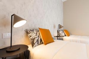 um quarto com 2 camas e uma mesa com um candeeiro em CaseOspitali - Glam Flat, nuovo trilocale di design zona Prada con box em Milão
