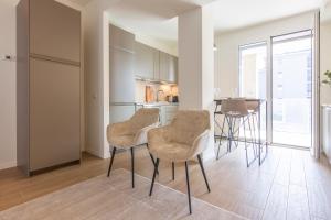 uma cozinha com cadeiras e uma mesa num quarto em CaseOspitali - Glam Flat, nuovo trilocale di design zona Prada con box em Milão