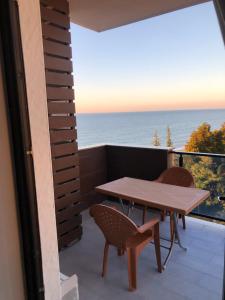 a table and chairs on a balcony with the ocean at Квартира на море Батуми in Makhinjauri