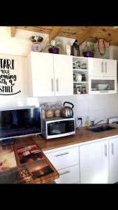 een keuken met witte kasten en een magnetron bij Casa amoblada hasta 3 personas in Merlo