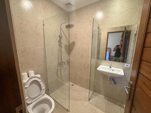 烏布的住宿－梅德阿薩家居酒店，男人拍着带卫生间和水槽的浴室的照片