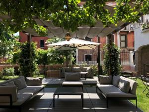 une terrasse avec des canapés et un parasol dans l'établissement Palazzo Morosini Degli Spezieri - Apartments, à Venise
